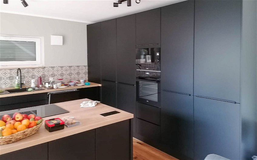 schwarze Küchenzeile mit Insel und Holz in Küche des Kern-Haus Modus in Halle Giebichenstein