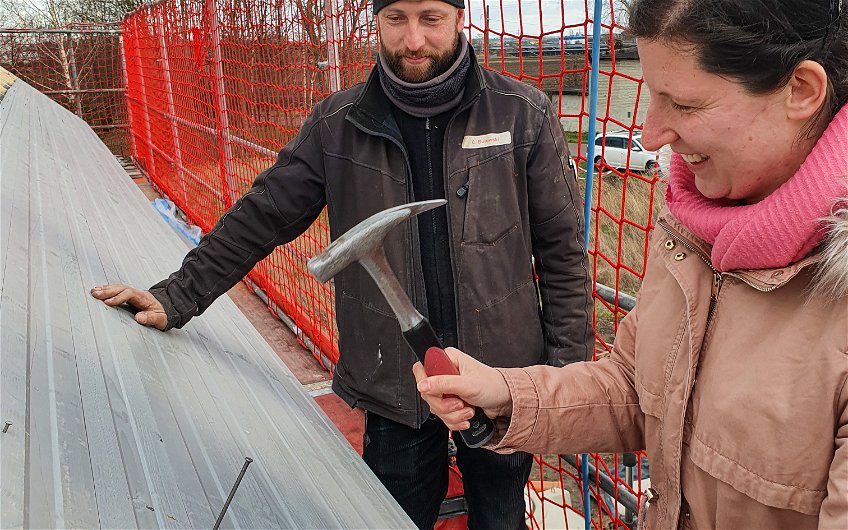 Bauherrin schlägt letzten Nagel in Dachstuhl des Kern-Haus Rohbaus in Halle Braschwitz