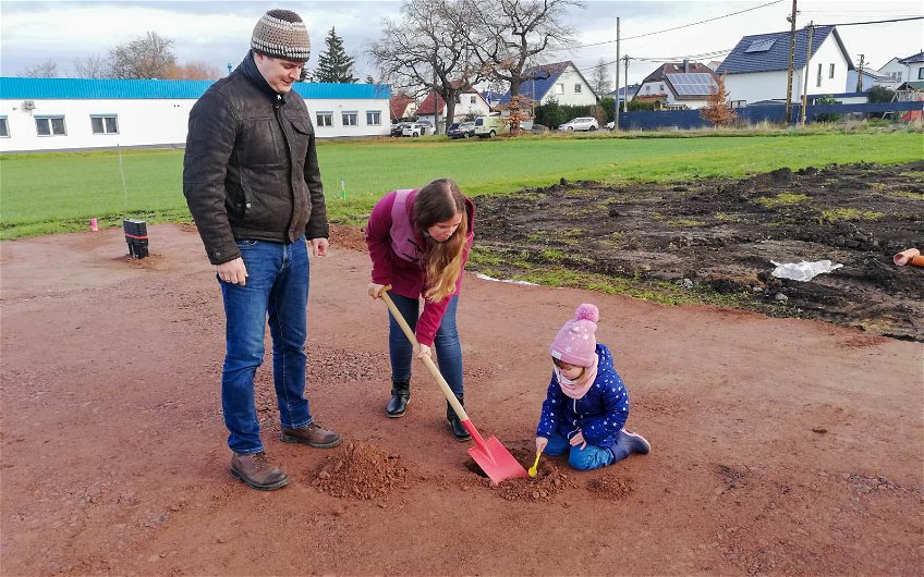 Bauherrin mit Mann und Kind hilft bei Grundsteinlegung für Kern-Haus in Halle Ammendorf