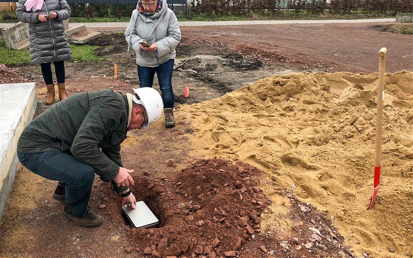 Bauherr legt Grundsteinkassette in Loch für Grundsteinlegung eines KErn-HAus Loop Classic in Halle Reideburg