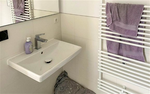 Gästebad mit hellen Fliesen sowie Waschbecken und Handtuchheizkörper in Kern-Haus Stadtvilla in Halle Reideburg