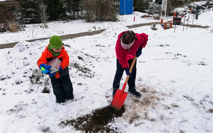 Kind hält Kassette und weiteres gräbt für Grundsteinlegung eines Kern-Haus Jara in Halle Ammendorf