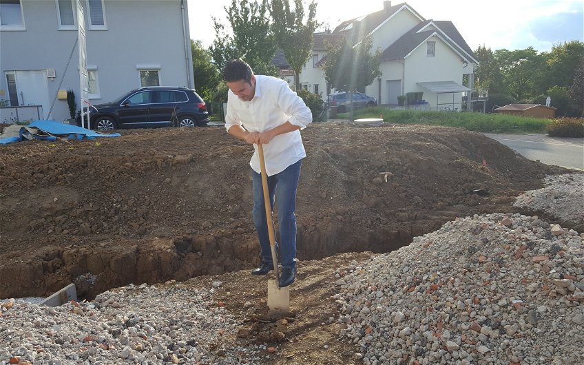 Bauherr gräbt das Loch bei der Grundsteinlegung für die frei geplante Doppelhaushälfte von Kern-Haus in Malsch