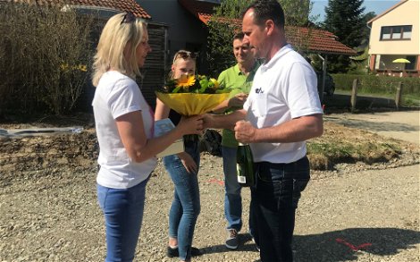 Mario Wilhelmi gratuliert und übergibt der Bauherrin einen Blumenstrauß.