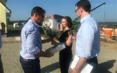 Mario Wilhelmi überreicht der Bauherrin einen Blumenstrauß.