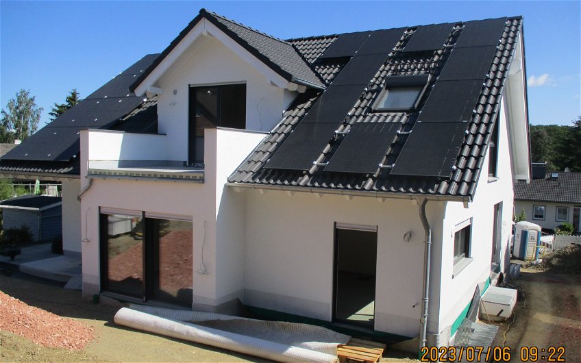Die Gartenseite des Hauses mit fertiggestellter Fassade und Fotovoltaikanlage.