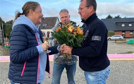 Mario Wilhelmi überreicht der Bauherrin einen Blumenstrauß und spricht Glückwünsche aus.