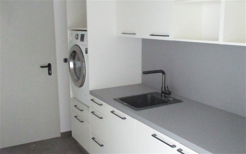 Die Waschmaschine und eine einfache Küchenzeile vervollständigen den Hauswirtschaftsraum.