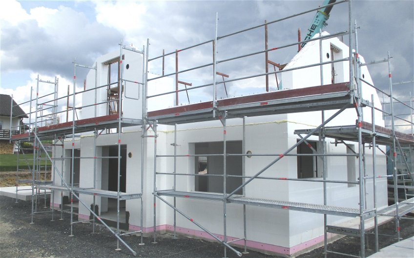 Für Zimmermann- und Dachdeckerarbeiten wird das Außengerüst mit zusätzlichen Sicherheitsmaßnahmen erweitert.