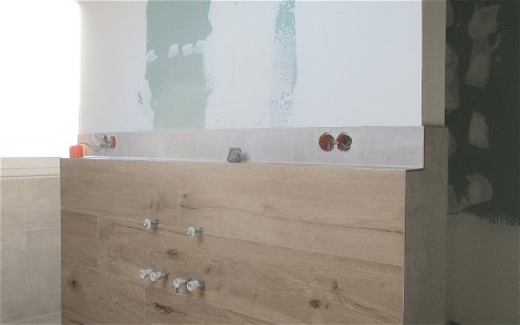 Die moderne Trennwand sorgt im Bad für eine optimale Platzierung des Doppel-Waschbeckens.