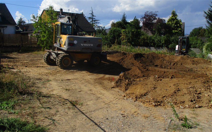 Unter Einsatz von mobilen Baugeräten wird Mutterboden abgetragen.