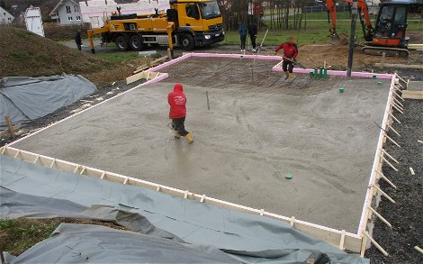 Die Bodenplatte wird von fleißigen Bauarbeitern betoniert.