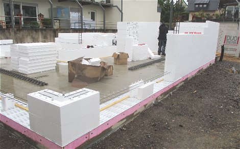 Baumaterial wird auf die Baustelle geliefert und auf der Bodenplatte verteilt.