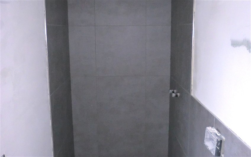 Der Duschbereich wird durch Spritzwasser mit wandhohen Fliesen geschützt.