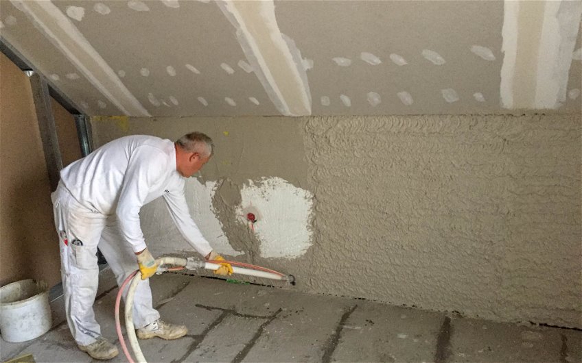 Putzer beim Auftragen des Innenputzes auf Außenwand des Kern-Haus Rohbau in Delitzsch