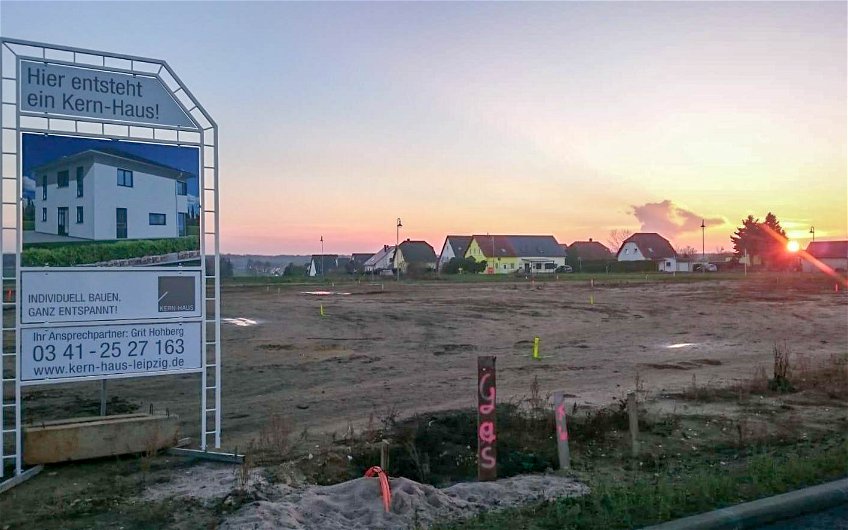 Baufeld mit Bauschild und Hausabsteckungen für Kern-Haus in Großpösna