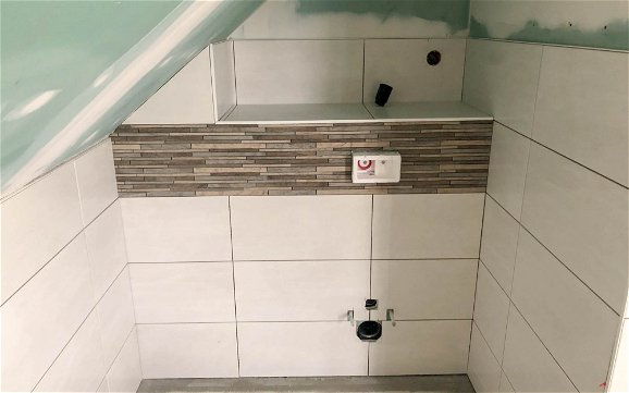 WC-Nische mit weißen und brauen Fliesen in Dachgeschossbad des Kern-Haus Rohbaus in Zschortau