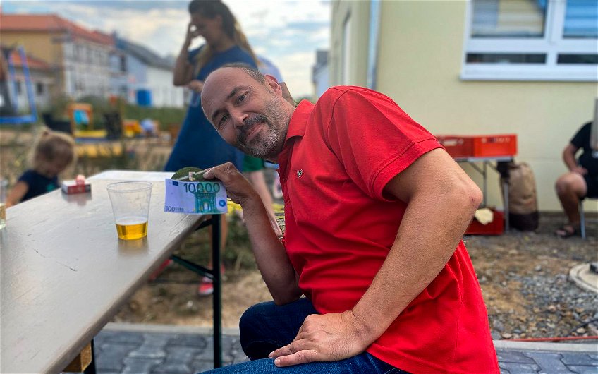 Verkaufsberater Jens Mischnik mit Bauherrengeschenk auf Einzugsfest für Kern-Haus Stadtvilla in Pegau