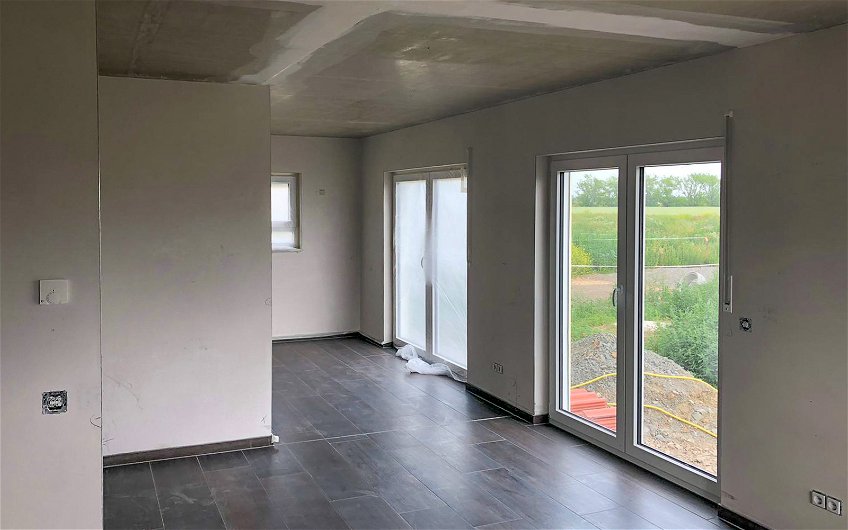 Wohnbereich mit offenen Fenstern und dunklem Bodenbelag in Kern-Haus Stadtvilla in Pegau