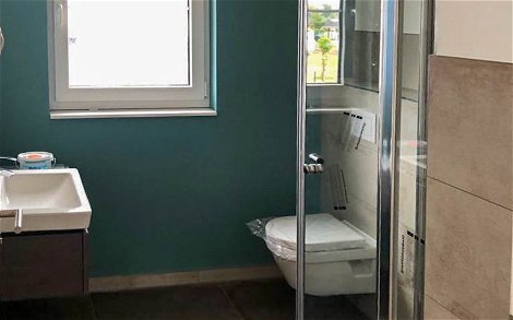 Bad mit Dusche mit dunklen Fliesen und türkiser Wandfarbe in Kern-Haus in Landsberg