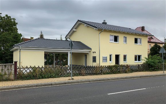 Fertig gestelltes Kern-Haus mit gelbem Anstrich und Carport in Delitzsch