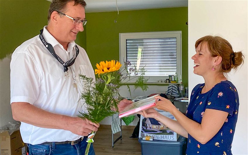 Bauherrin übergibt Bauleiter sommerliches Geschenk zur Hausübergabe des Kern-Haus Aura in Großkugel