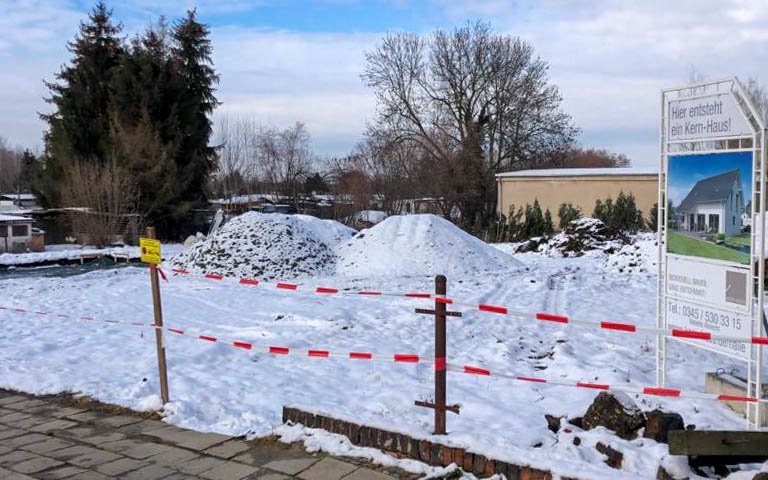Grundstück mit Schnee und Bauschild für Kern-Haus Family in Lucka