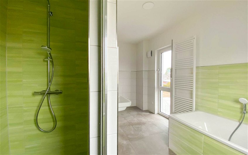 grün geflieste Dusche mit Badewanne in Kern-Haus Stadtvilla Baleo in Eilenburg