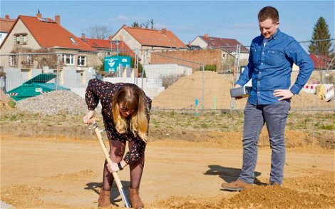 Bauherrin gräbt Loch für Grundsteinkassette für Kern-Haus Stadtvilla in Pegau