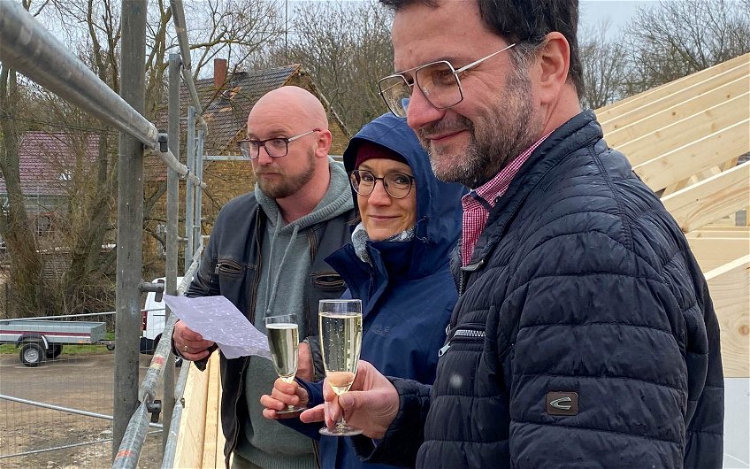 Verkaufsberater Ronny Hartmann mit Bauherren auf Richtfest für Kern-Haus Bungalow in Brodau
