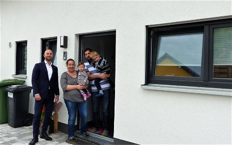 Verkaufsberater Bernd Laatz und Baufamilie an der Haustür des Kern-Hauses Komfort in Linkenheim-Hochstetten