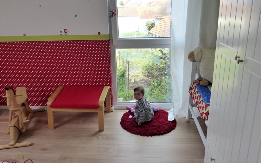 Tochter der Bauherren am Fenster ihres Kinderzimmers im Kern-Haus Komfort in Linkenheim-Hochstetten