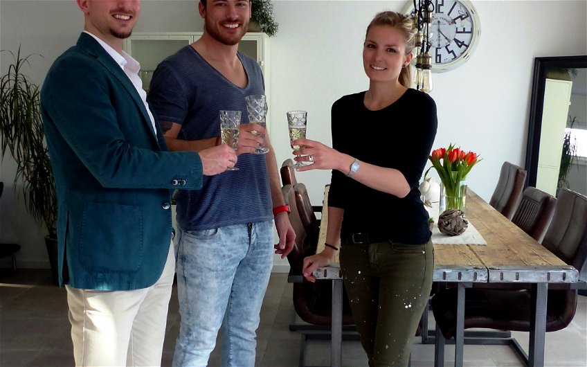 Verkaufsberater Bernd Laatz und Bauherrenpaar beim Anstoßen mit einem Glas Sekt in der Kern-Haus-Stadtvilla Signus in Otterberg