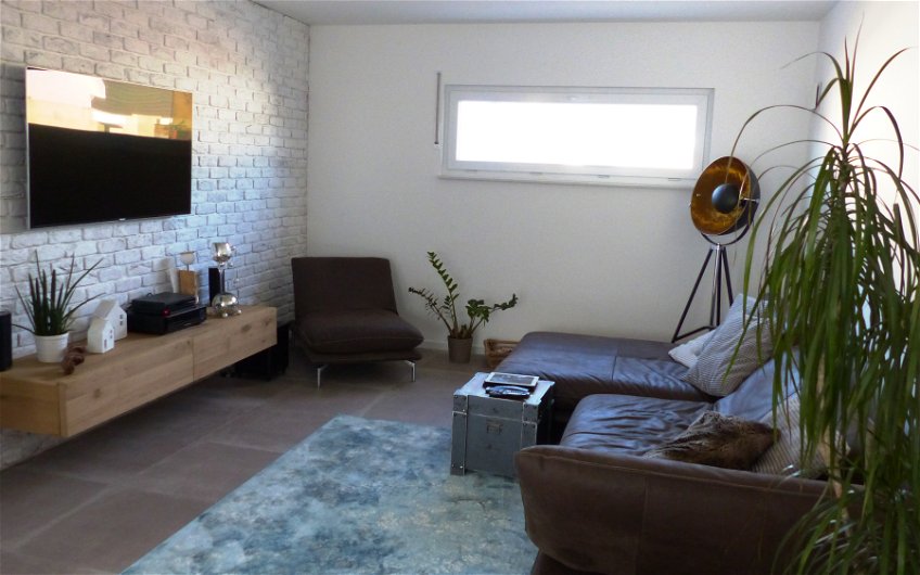 Wohnzimmer der Kern-Haus-Stadtvilla Signus in Otterberg mit Couch, Sideboard und Fernseher
