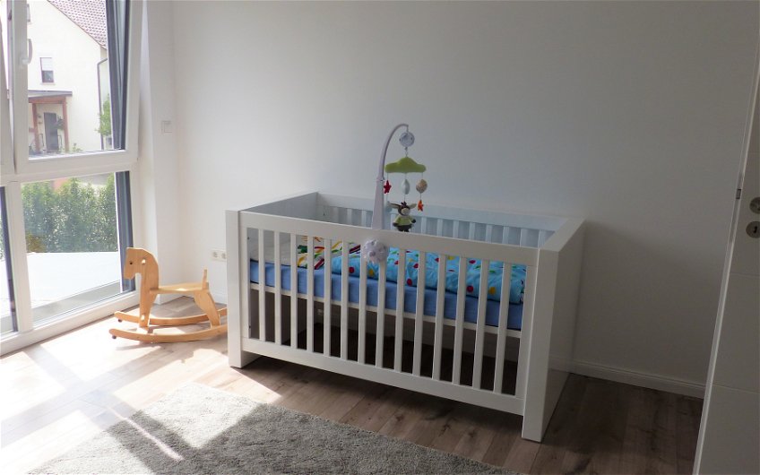 Kinderbett und Schaukelstuhl im Kinderzimmer des Einfamilienhauses Komfort von Kern-Haus in Neupotz