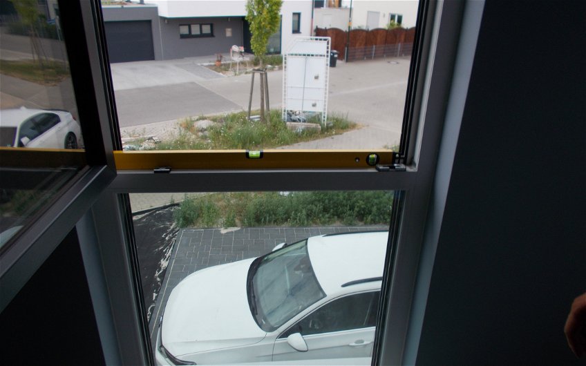 Geöffnetes Fenster mit aufliegender Wasserwaage bei der Endabnahme in der Kern-Haus-Stadtvilla Signus in Dettenheim-Rußheim