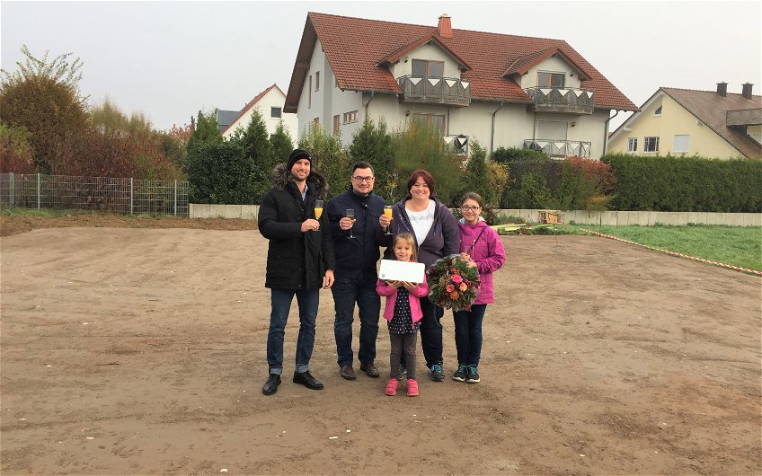 Baufamilie mit Verkaufsberater Bernd Laatz bei der Grundsteinlegung für das individuell geplante Einfamilienhaus Signum von Kern-Haus in Römerberg
