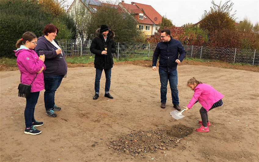 Tochter gräbt bei der Grundsteinlegung für das individuell geplante Einfamilienhaus Signum von Kern-Haus in Römerberg