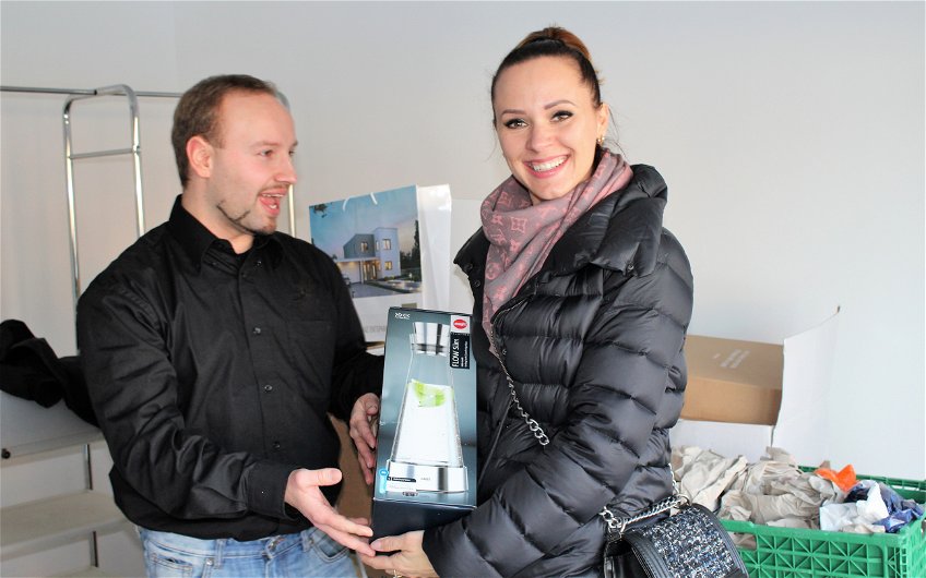 Bauleiter Yves Balster überreicht den Bauherren ein Geschenk zur Hausübergabe.