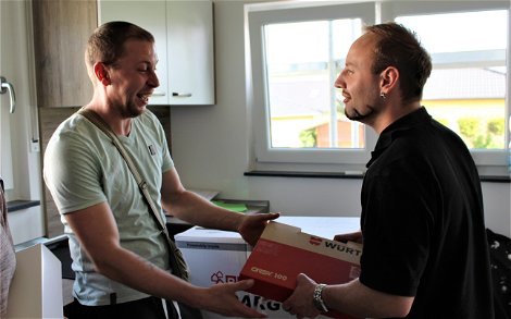 Kern-Haus-Bauleiter Yves Balster übergibt dem Bauherren einen Dübelkoffer der Firma Würth