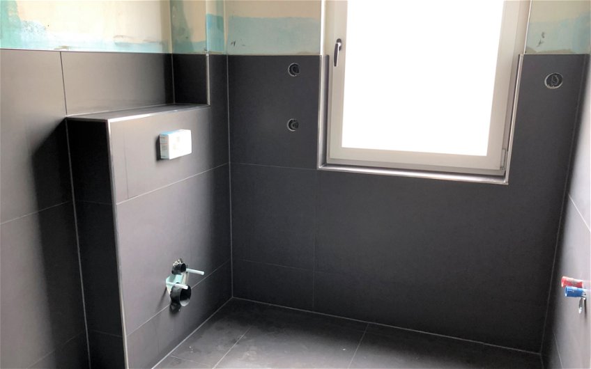 Badezimmer mit dunkelgrauen Fliesen in einer Kern-Haus-Stadtvilla