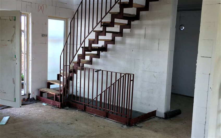 Offener Flur mit Stahltreppe ins Obergeschoss und Keller führend.