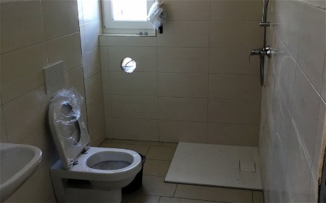 Blick in das Gäste-WC mit Dusche ohne Duschwand.
