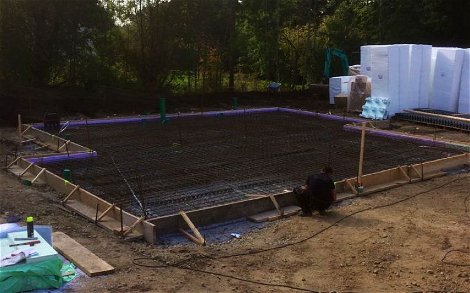 Blick auf Bauplatz mit Holzschalung und Stahlbewehrung für die Bodenplatte.