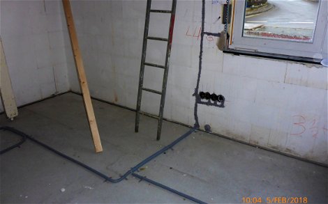 Rohbauraum mit verlegten Elektroleitungen in Wandschlitzen und auf dem Fussboden.