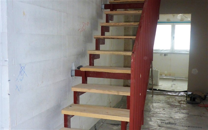 Rote Stahltreppe mit provisorischen Stufen aus Holz.