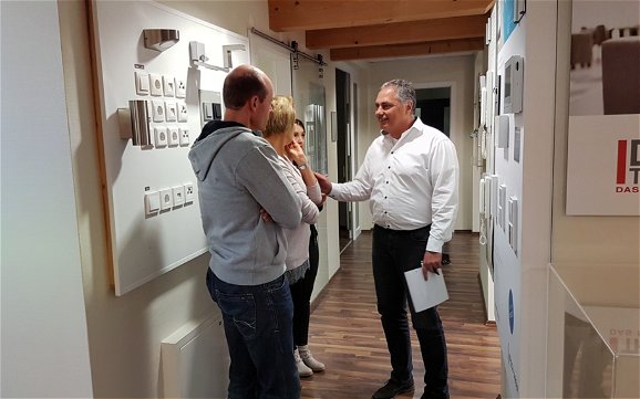 Bauherren mit Architektin und Geschäftsführer Frank Krämer vor Musterbeispielen verschiedener Elektroprogramme.