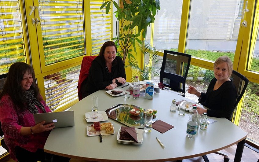 Bauherrin in Begleitung zusammen mit Architektin am kleinen Konferenztisch sitzend.