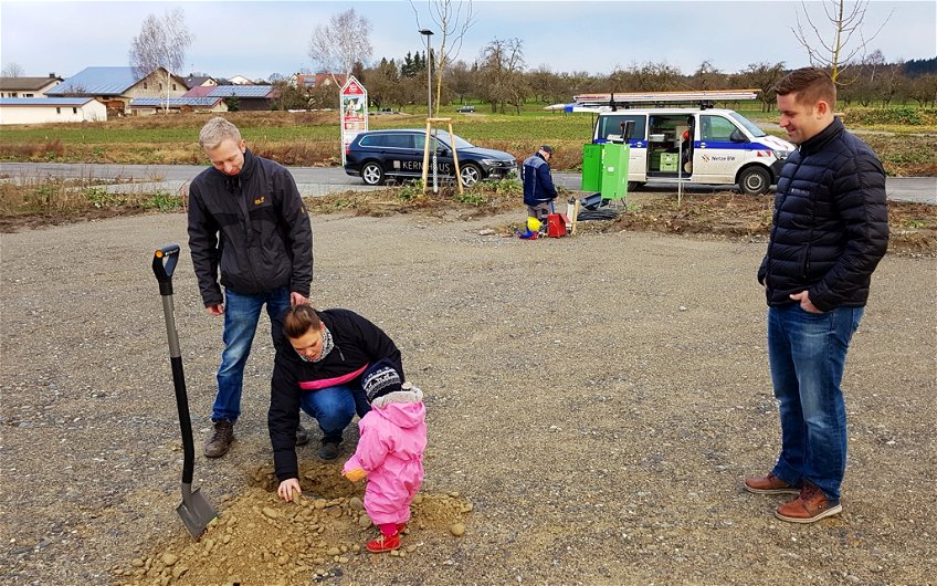 Bauherren mit Kind und Bauleiter Oliver Marquart beim Betrachten der Grube für den Grundstein