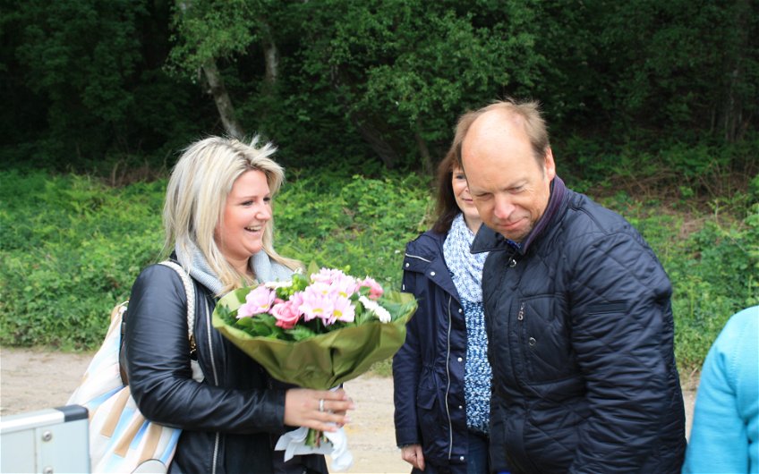 Der Kern-Haus Rhein-Ruhr Geschäftsführer Axel Kaltenbach übergibt einen Blumenstrauß an die Bauherrin Verena.